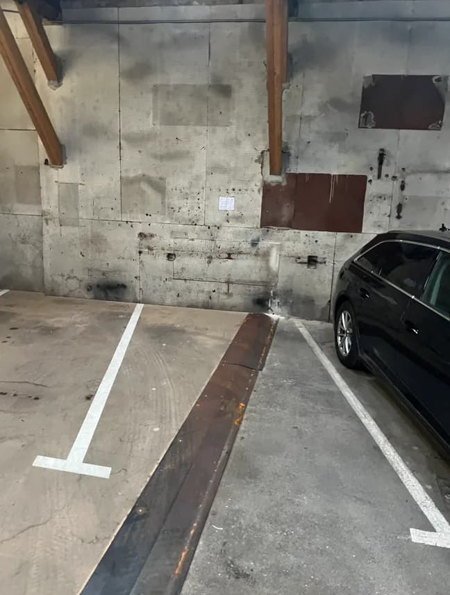 Local de stationnement avec mur en béton et plafond en bois.