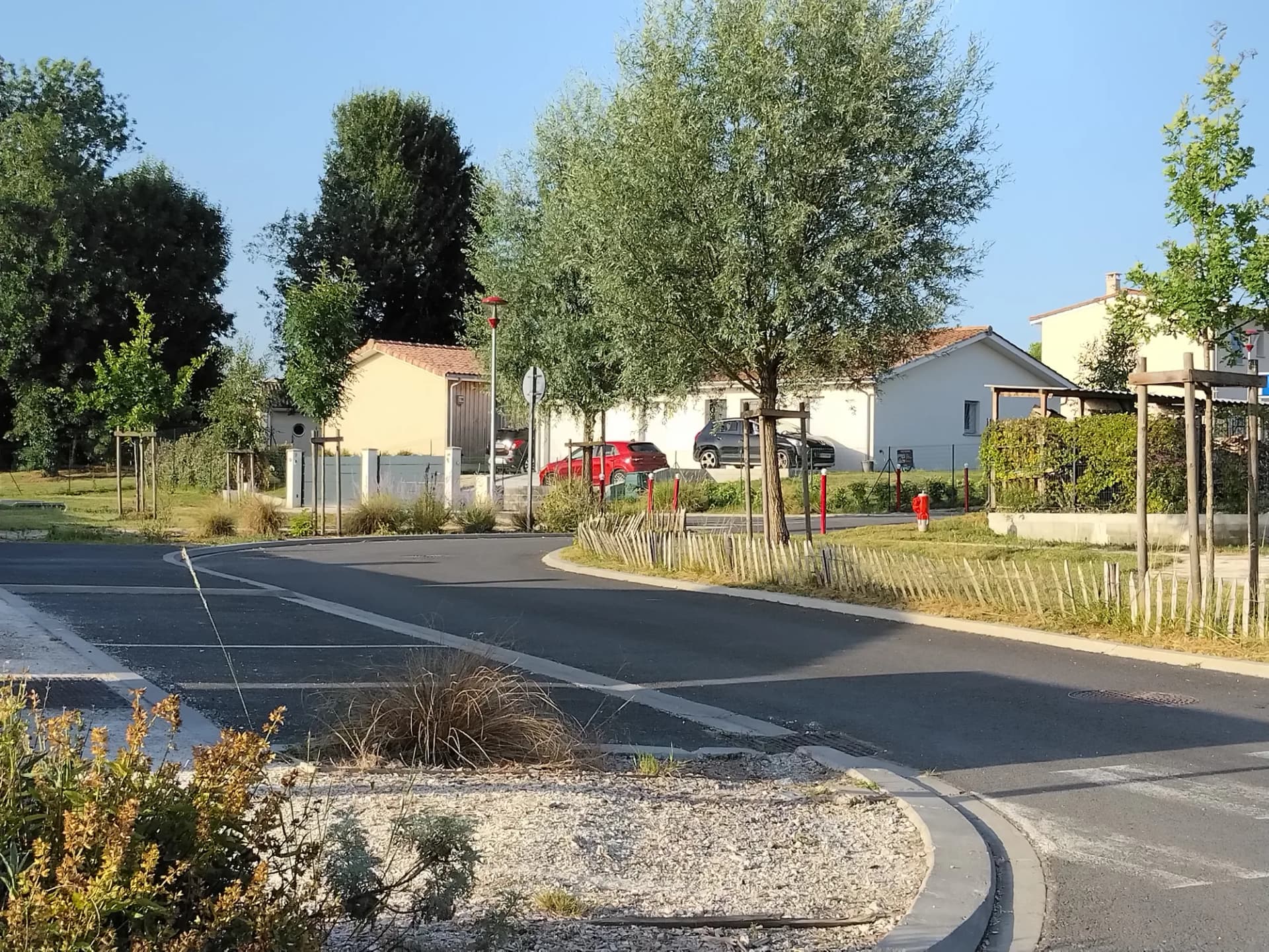 Vue d'un quartier résidentiel avec maisons, arbres et route en courbe.