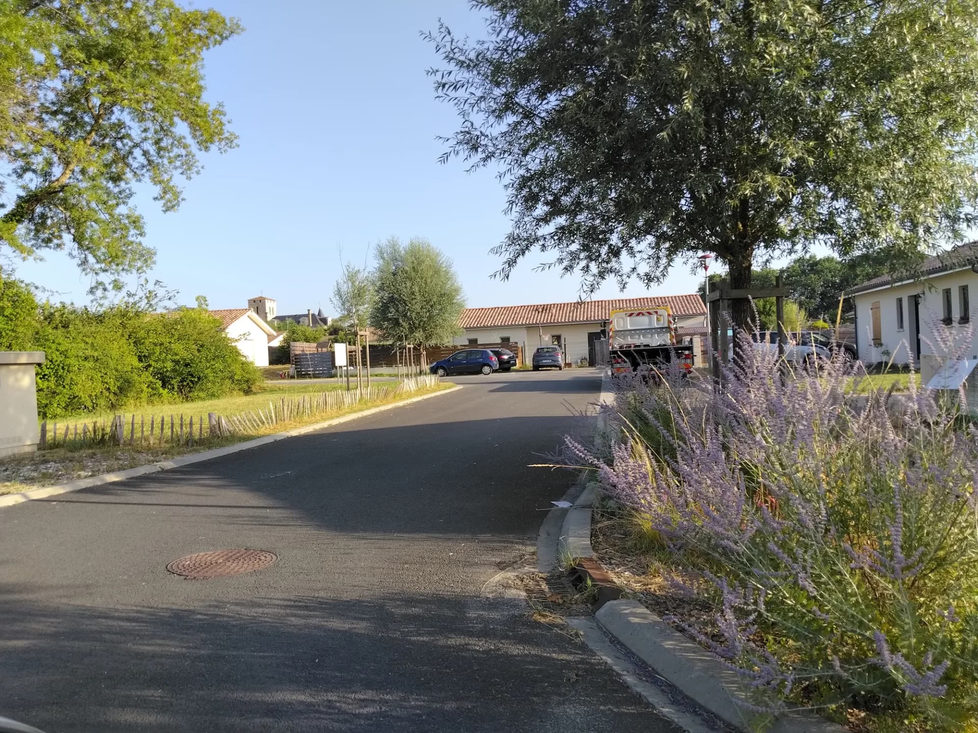 Entrée d'une maison avec jardin et stationnement, arborée et ensoleillée.